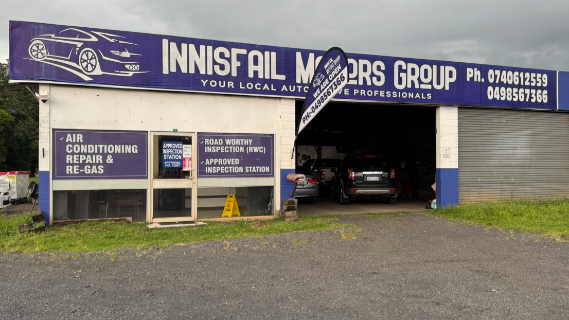 The blue and white Innisfail Motors Group workshop with its signage and open roller door