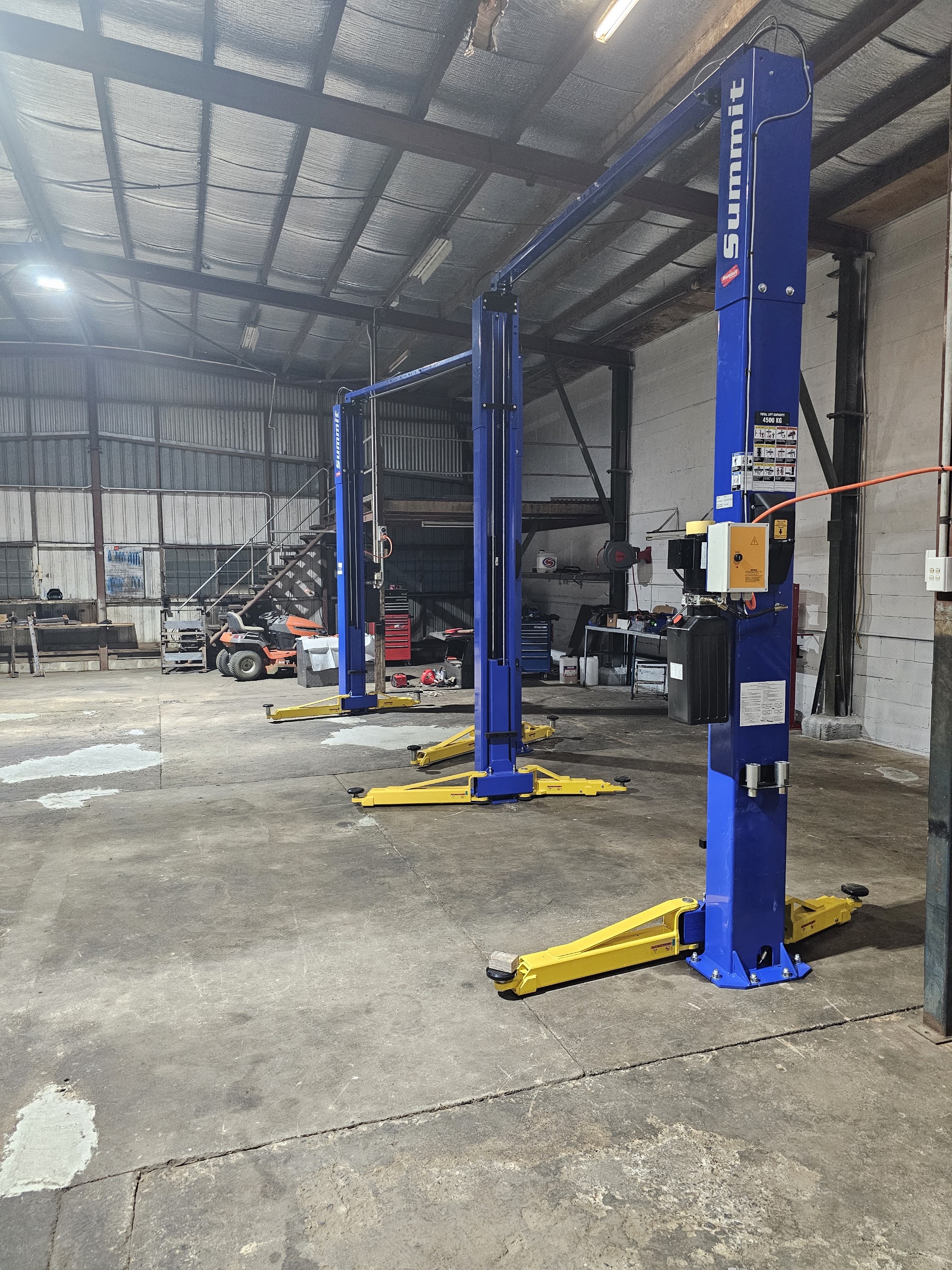 Two blue Summit two-post vehicle hoists in the Innisfail Motors Group workshop
